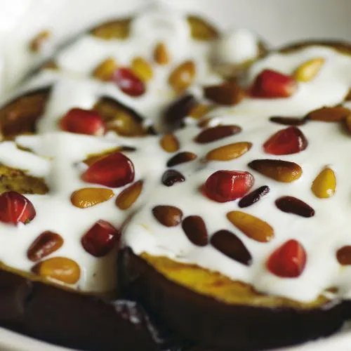 Plakjes aubergine met granaatappel, yoghurt en tahini