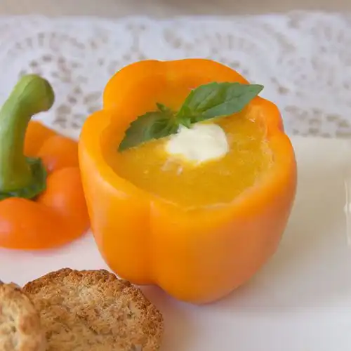 Koude oranje paprikasoep met basilicum